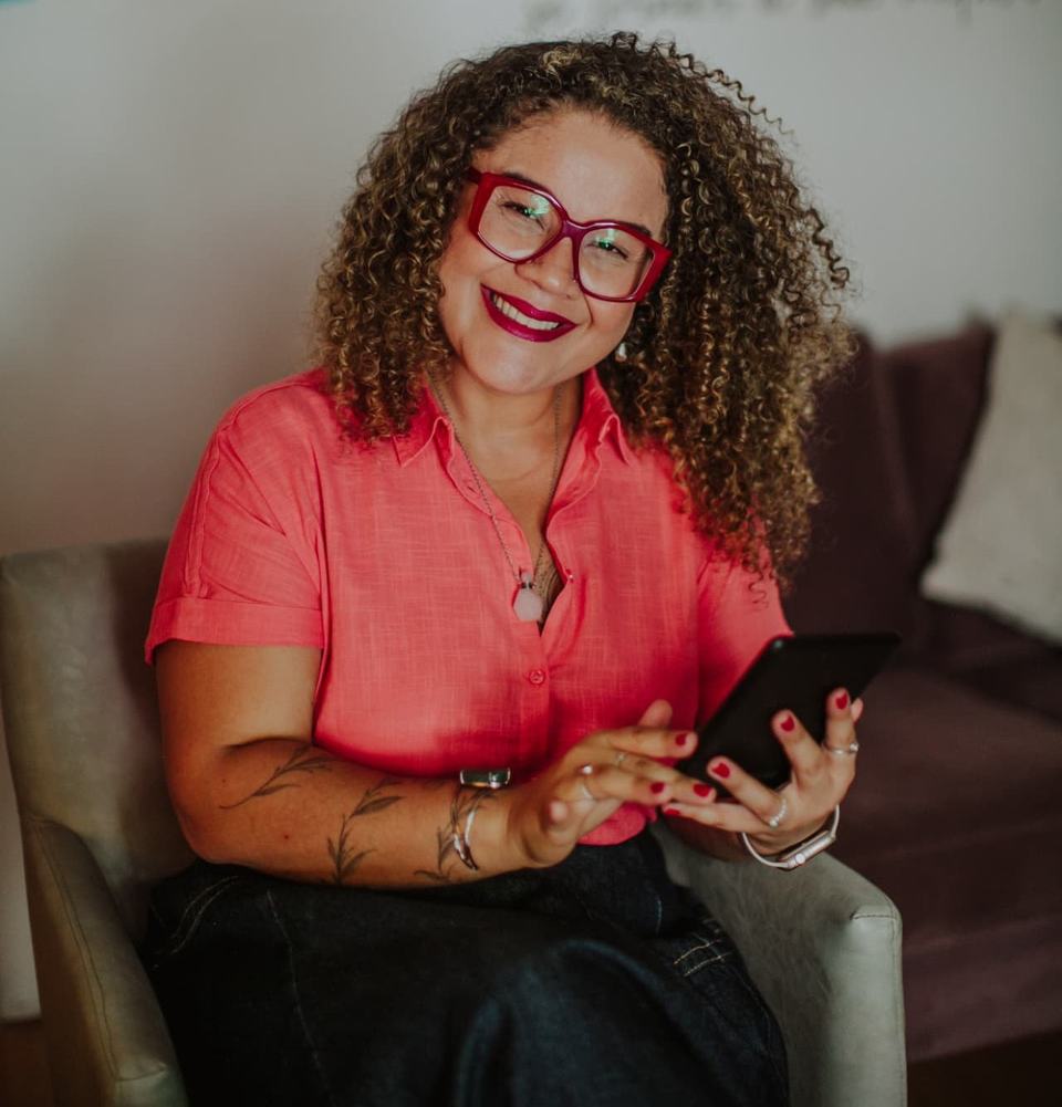 Clarice Sousa, especialista em liderança, sorrindo com um tablet nas mãos